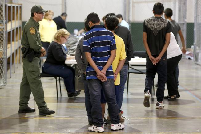 Boys wait in line to make a phone call as they are joined by hundreds of mostly Central American immigrant children that are being processed and held at the U.S. Customs and Border Protection Nogales Placement Center on Wednesday, June 18, 2014, in Nogales, Ariz. CPB provided media tours Wednesday of two locations in Brownsville, Texas, and Nogales, that have been central to processing the more than 47,000 unaccompanied children who have entered the country illegally since Oct. 1. (AP Photo/Ross D. Franklin, Pool)