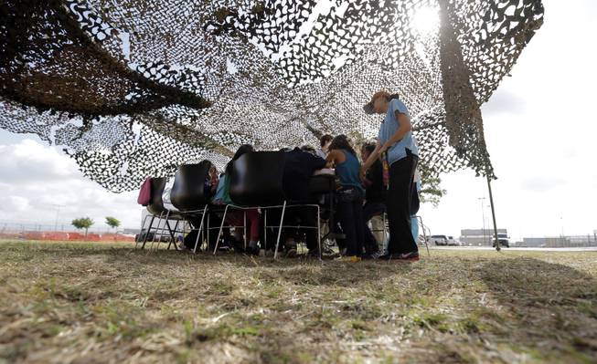 Detainees do art work under a camouflage tent at a U.S. Customs and Border Protection processing facility, Wednesday, June 18, 2014, in Brownsville,Texas. CPB provided media tours Wednesday of two locations in Brownsville and Nogales, Ariz. that have been central to processing the more than 47,000 unaccompanied children who have entered the country illegally since Oct. 1. (AP Photo/Eric Gay, Pool)