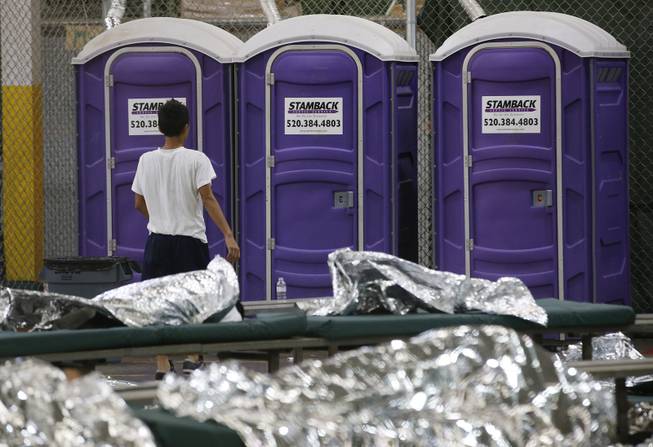 A young boy walks over to use the toilet while in his holding area where hundreds of mostly Central American immigrant children are being processed and held at the U.S. Customs and Border Protection Nogales Placement Center on Wednesday, June 18, 2014, in Nogales, Ariz. CPB provided media tours Wednesday of two locations in Brownsville, Texas, and Nogales, that have been central to processing the more than 47,000 unaccompanied children who have entered the country illegally since Oct. 1. (AP Photo/Ross D. Franklin, Pool)