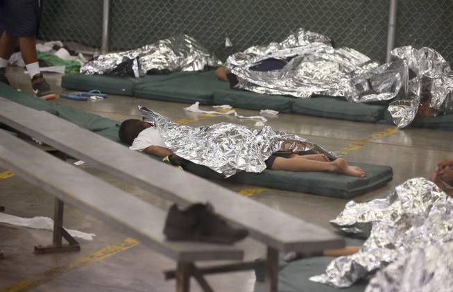 Young boys sleep in a holding cell where hundreds of mostly Central American immigrant children are being processed and held at the U.S. Customs and Border Protection Nogales Placement Center on Wednesday, June 18, 2014, in Nogales, Ariz. CPB provided media tours Wednesday of two locations in Brownsville, Texas, and Nogales, that have been central to processing the more than 47,000 unaccompanied children who have entered the country illegally since Oct. 1. (AP Photo/Ross D. Franklin, Pool)