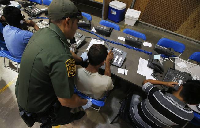 A U.S. Customs and Border Protection officer helps out a few boys who are trying to make phone calls as they are joined by hundreds of mostly Central American immigrant children that are being processed and held at the U.S. Customs and Border Protection Nogales Placement Center on Wednesday, June 18, 2014, in Nogales, Ariz. CPB provided media tours Wednesday of two locations in Brownsville, Texas, and Nogales, that have been central to processing the more than 47,000 unaccompanied children who have entered the country illegally since Oct. 1. (AP Photo/Ross D. Franklin, Pool)