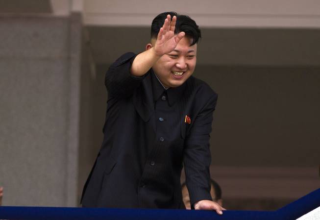 In this July 27, 2013, file photo, North Korean leader Kim Jong Un leans over a balcony and waves to Korean War veterans cheering below at the end of a mass military parade on Kim Il Sung Square in Pyongyang to mark the 60th anniversary of the Korean War armistice. North Korea is warning that the release of a new American comedy about a plot to assassinate leader Kim Jong Un would be an "act of war."