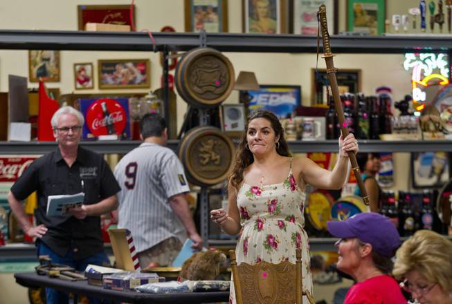 Marie McManus shows off a samurai sword currently up for bid during a one-day live auction hosted by Victorian Casino Antiques on Saturday, June 28, 2014. In cooperation with McManus Auctions, the showroom featured almost 600 lots of toys, coin-operated machines, clocks, advertising art, gaming collectibles and much more.
