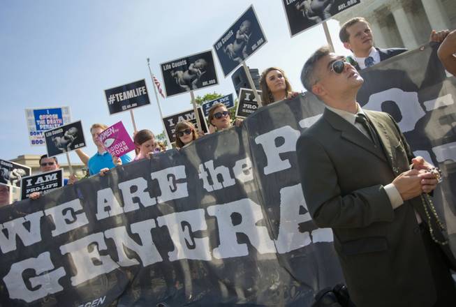 Michael Hichborn kneels and prays as he joins demonstrators while waiting for the Supreme Court's decision on the Hobby Lobby case outside the Supreme Court in Washington, Monday, June 30, 2014. The Supreme Court says corporations can hold religious objections that allow them to opt out of the new health law requirement that they cover contraceptives for women.