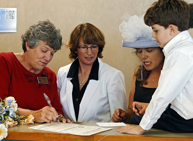 Denver County Clerk Debra Johnson, left, signs the marriage license of Fran Simon and Anna Simon as their son Jeremy watches at the Denver Clerk's office on Thursday, July 10, 2014. The Simons who have been together 11 years were united Thursday as the Denver County Clerks began issuing license to same sex couples.