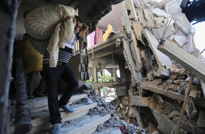 Palestinians carry belongings in a house after it was hit by an Israeli missile strike in Gaza City, Friday, July 11, 2014. Israel launched the Gaza offensive to stop incessant rocket fire that erupted after three Israeli teenagers were kidnapped and killed in the West Bank and a Palestinian teenager was abducted and burned to death in an apparent reprisal attack. The military says it has hit more than 1,100 targets already, mostly what it identified as rocket-launching sites, bombarding the territory on average every five minutes.