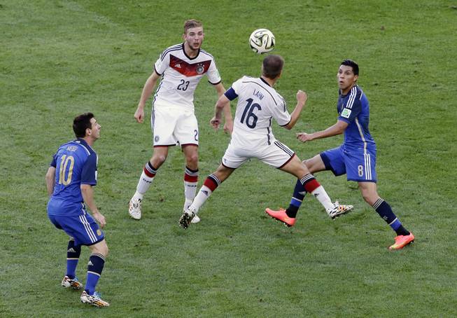 Argentina's Lionel Messi eyes the ball as Germany's Philipp Lahm goes for a header and Argentina's Enzo Perez, right, and Germany's Christoph Kramer (23) look on during the World Cup final soccer match between Germany and Argentina at the Maracana Stadium in Rio de Janeiro, Brazil, Sunday, July 13, 2014.