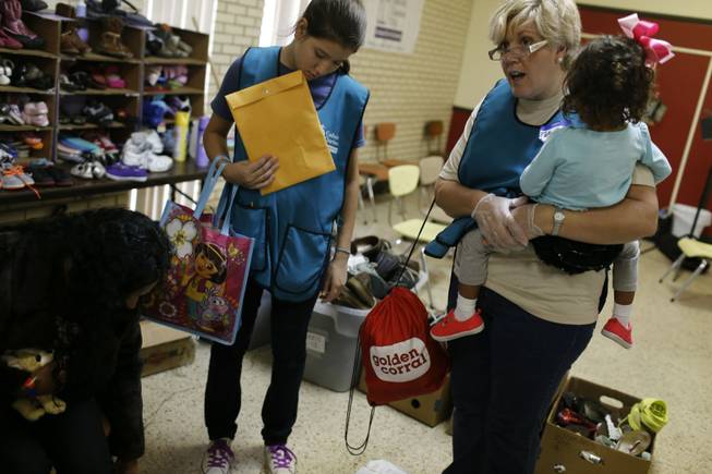 Estela Gonzalez, right, and her daughter Mikaela, center, assist Maria Castro, left, and her 2-year-old daughter Natalia Maravillaga. Castro and her daughter are from Honduras and traveled across Mexico and into Texas en route to family in Stanford, Conn. Gonzalez volunteers with a group in McAllen, Texas, that comes to the aid of immigrants.