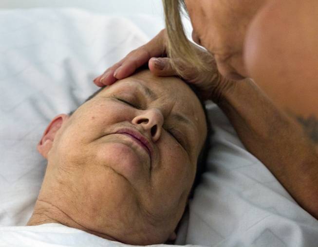 Linda Rolain is soothed by her sister from her hospital bed in their living room just days before she passed away following brain surgery in May on Wednesday, June 25, 2014. She should have had surgery much sooner but due to the problems on the exchange she wasn't able to receive insurance until mid May.