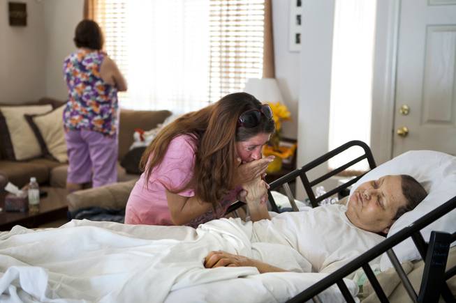 Linda Rolain is soothed by friend Toni at her hospital bed in their living room just days before she passed away following brain surgery in May on Wednesday, June 25, 2014. She should have had surgery much sooner but due to the problems on the exchange she wasn't able to receive insurance until mid May.
