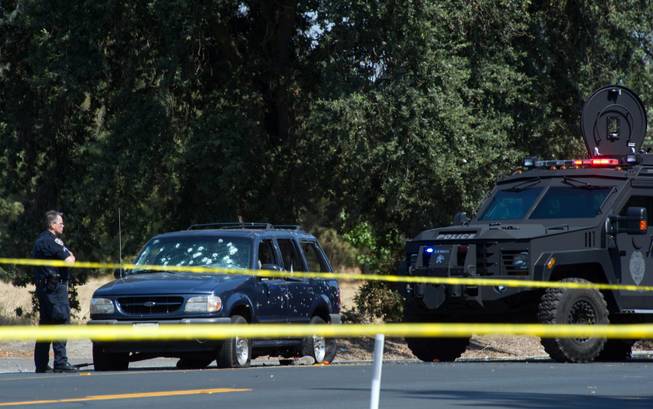 Stockton Police officers examine the scene where bank robbery suspects with hostages were stopped Wednesday, July 16, 2014. Cars and houses were riddled with bullets during a high-speed chase and hostages were thrown from a fleeing SUV after a bank robbery that led to the deaths of a hostage and two robbers, police said.