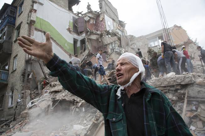 AP10ThingsToSee - Igor Chernetsov, whose wife was killed in a building demolished by an airstrike, gestures near the collapsed structure in Snizhne, 100 kilometers east of Donetsk, eastern Ukraine, Tuesday, July 15, 2014. At least nine civilians were killed in the attack, rescue workers said.