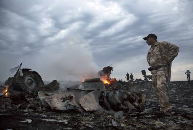 People walk amongst the debris, at the crash site of a passenger plane near the village of Grabovo, Ukraine, Thursday, July 17, 2014. A Ukrainian official said a passenger plane carrying 295 people was shot down Thursday as it flew over the country and plumes of black smoke rose up near a rebel-held village in eastern Ukraine. Malaysia Airlines tweeted that it lost contact with one of its flights as it was traveling from Amsterdam to Kuala Lumpur over Ukrainian airspace.
