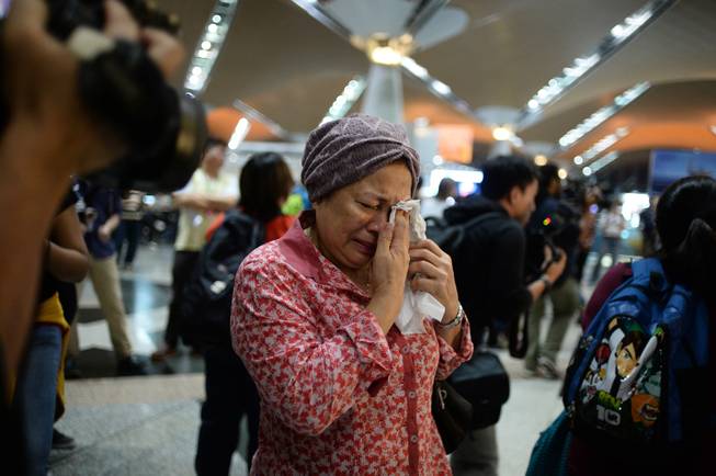 A woman reacts to news regarding a Malaysia Airlines plane that crashed in eastern Ukraine at Kuala Lumpur International Airport in Sepang, Malaysia, Friday, July 18, 2014. Ukraine said a passenger plane carrying 295 people was shot down Thursday as it flew over the country, and both the government and the pro-Russia separatists fighting in the region denied any responsibility for downing the plane.