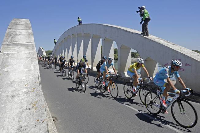 Photographers take pictures of the pack with Italy's Vincenzo Nibali, wearing the overall leader's yellow jersey, as it passes over a bridge during the twelfth stage of the Tour de France cycling race over 185.5 kilometers (115.3 miles) with start in Bourg-en-Bresse and finish in Saint-Etienne, France, Thursday, July 17, 2014.