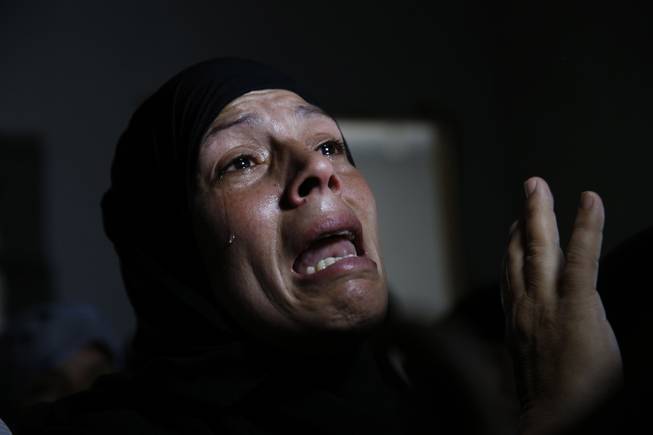 AP10ThingsToSee - A Palestinian mourner cries after the bodies of Mousa Abu Muamer, 56, and his son Saddam, 27, were brought in for their funeral on Monday, July 14, 2014, in the Gaza Strip. The two were killed in an overnight Israeli missile strike at their house in the outskirts of the town of Khan Younis, southern Gaza Strip.