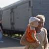 Photo: A man holds a baby as he walks next to a refrigera Photo: A man holds a baby as he walks next to a refrigera
