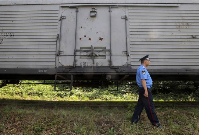 A police officer walks past a refrigerated train loaded with bodies of the passengers of Malaysian Airlines flight MH17 at Kharkiv railway station, Ukraine, Tuesday, July 22, 2014. The train carrying the remains of people killed in the Malaysia Airlines crash arrived in the eastern Ukrainian city of Kharkiv on Tuesday on their way to the Netherlands, a journey which has been agonizingly slow for relatives of the victims.