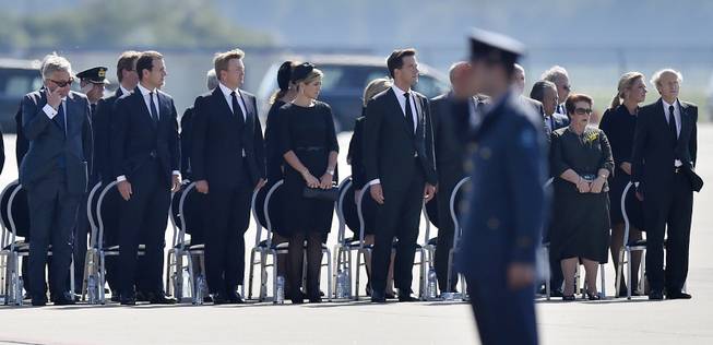 King Willem Alexander, 3rd from left, his wife Maxima and prime minister Mark Rutte, stand during a ceremony to mark the return of the first bodies, of passengers and crew killed in the downing of Malaysia Airlines Flight 17, from Ukraine at Eindhoven military air base, Netherlands, Wednesday, July 23, 2014. After being removed from the planes, the bodies are to be taken in a convoy of hearses to a military barracks in the central city of Hilversum, where forensic experts will begin the painstaking task of identifying the bodies and returning them to their loved ones.