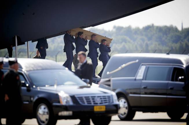 Pallbearers carry a coffin out of a military transport plane during a ceremony to mark the return of the first bodies, of passengers and crew killed in the downing of Malaysia Airlines Flight 17, from Ukraine at Eindhoven military air base, Netherlands, Wednesday, July 23, 2014. After being removed from the planes, the bodies were taken in a convoy of hearses to a military barracks in the central city of Hilversum, where forensic experts will begin the painstaking task of identifying the bodies and returning them to their loved ones.