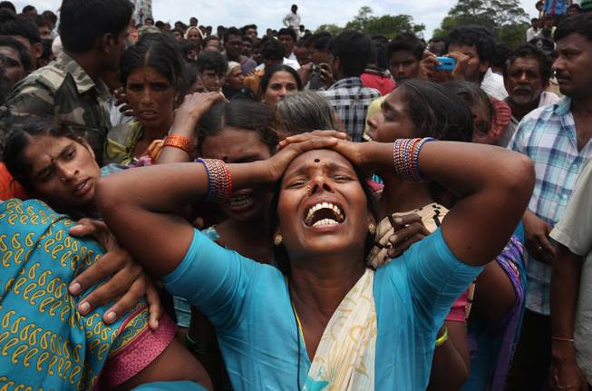 AP10ThingsToSee - A relative of a victim cries at the site of a train that crashed into a school bus in Medak district in the southern Indian state of Telengana, Thursday, July 24, 2014. Twelve children were killed in the crash at an unmanned railroad crossing in southern India, police said.