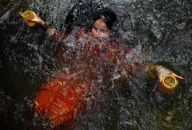 AP10ThingsToSee - A Hindu devotee takes holy dip as she collects holy water from the Bagmati river during the Bol Bom pilgrimage in Sundarijaal on the outskirts of Katmandu, Nepal, Monday, July 21, 2014. Devotees walk miles barefooted before offering the water at the Pashupatinath lord Shiva temple in Katmandu.
