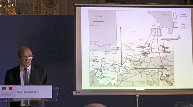 French defense minister Jean-Yves Le Drian addresses reporters during a press conference held at the foreign ministry in Paris, Friday July 25, 2014 after a plane crashed in Mali. At least 116 people were killed in Thursday’s disaster, nearly half of whom were French. One of two black boxes was recovered from the wreckage in the Gossi region of Mali near the border with Burkina Faso, and was taken to the northern city of Gao, where a French contingent is based. The drawing projected at right shows the means used for the searches by French Army.