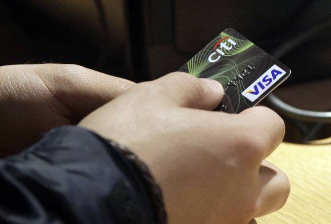 In this May 9, 2012, file photo, a Visa credit card is tendered at the opening of the Superdry store in New York's Times Square. More than 35 percent of Americans have debts and unpaid bills that have been reported to collection agencies, according to a study released Tuesday, July 29, 2014, by the Urban Institute.