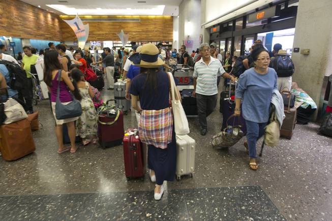Crowds line up inside the departures terminal at the Honolulu International Airport in Honolulu on Thursday, Aug. 7, 2014. With Iselle, Hawaii is expected to take its first direct hurricane hit in 22 years. Tracking close behind it is Hurricane Julio. Hawaiian Airlines announced Thursday they are waiving change fees for passengers trying to leave before the hurricanes hit the islands.