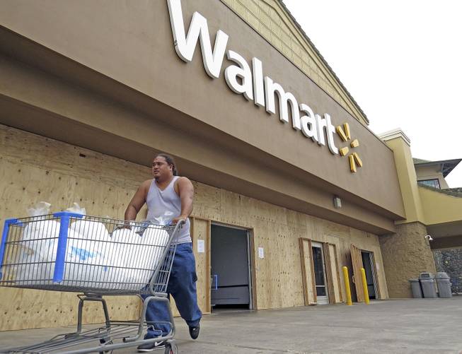 A man pushes a shopping cart outside of a Walmart store that boarded its entrance and closed early in Kailua-Kona, Hawaii, Thursday, Aug. 7, 2014, as the area prepares for Hurricane Iselle. Hurricane Iselle is expected to arrive on the Big Island on Thursday evening, bringing heavy rains, winds gusting up to 85 mph and flooding in some areas. Weather officials changed their outlook on the system Wednesday after seeing it get a little stronger, giving it enough oomph to stay a hurricane as it reaches landfall.