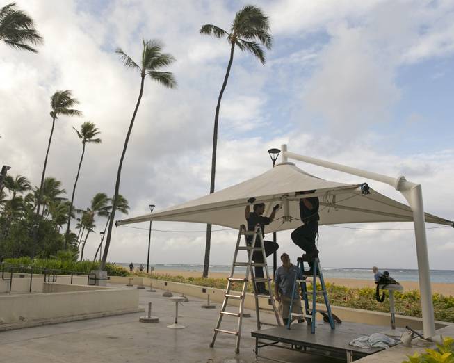 In preparation for heavy winds, workers at the Hale Koa Hotel remove an awning from an outdoor stage in Honolulu on Friday, Aug, 8, 2014. Iselle came ashore early Friday as a weakened tropical storm, while Hurricane Julio, close behind it, strengthened and is forecasted to pass north of the islands. Iselle is the first tropical storm to hit the state in 22 years.
