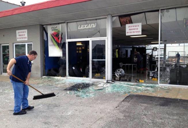 Cleanup begins Monday, Aug. 11, 2014 after a night of unrest following a candle-light vigil for 18-year-old shooting victim Michael Brown left broken glass and burned stores in Ferguson, Mo. Police said Brown, who was unarmed, was fatally shot Saturday in a scuffle with an officer.