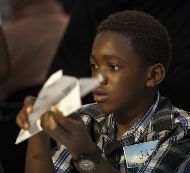 Jai Leveston, 12, with team Hudson News joins others in folding their airplanes before the Paper Plane Palooza competition begins at McCarran International Airport on Tuesday, August 12, 2014. He would go on to win the long distance throw as a member of the Boys & Girls Clubs of Southern Nevada.