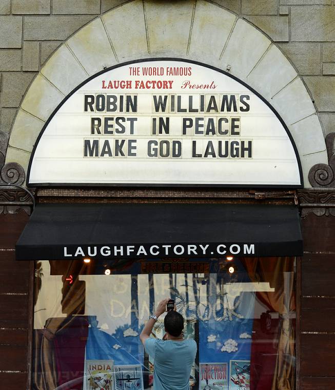 A man takes a photo of a the marquee of the Laugh Factory with a message in memory of actor Robin Williams displayed, in the Hollywood district of Los Angeles Monday, Aug. 11, 2014. Williams, the Academy Award winner and comic supernova whose explosions of pop culture riffs and impressions dazzled audiences for decades died Monday in an apparent suicide at his San Francisco Bay area home. He was 63.