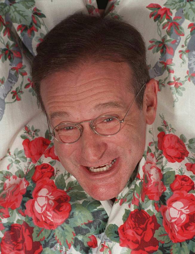 In this Nov. 15, 1997 file photo, Robin Williams extends his head between curtains in a New York hotel. Williams, a brilliant shapeshifter who could channel his frenetic energy into delightful comic characters like "Mrs. Doubtfire" or harness it into richly nuanced work like his Oscar-winning turn in "Good Will Hunting," died Monday in an apparent suicide. He was 63. Williams was pronounced dead at his San Francisco Bay Area home Monday, according to the sheriff's office in Marin County, north of San Francisco.