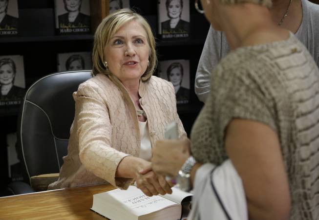 Former Secretary of State Hillary Rodham Clinton shakes hands with a customer at Bunch of Grapes Bookstore, in Vineyard Haven, Mass., on the island of Martha's Vineyard, Wednesday, Aug. 13, 2014, during a book signing event for her memoir "Hard Choices." Clinton says she's looking forward to hugging out her differences with President Barack Obama. Obama's former secretary of state told reporters Wednesday that she's proud to have served with him despite some differences of opinion.