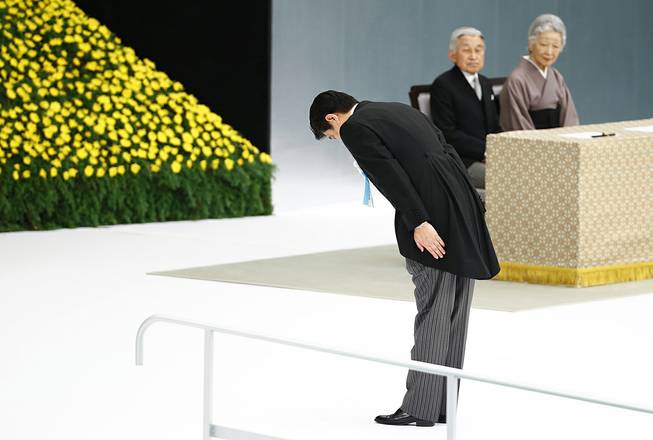 Japanese Prime Minister Shinzo Abe bows before the main altar decorated with huge bank of chrysanthemums as he offers prayers for the war dead during a memorial ceremony at Budokan Martial Arts Hall in Tokyo, Friday, Aug. 15, 2014. Abe visited Yasukuni in December 2013, drawing widespread criticism. But Aug. 15 is a key date as it marks the day in 1945, when Emperor Hirohito announced the surrender on the radio. Japan on Friday, marked the 69th anniversary of its surrender, ending the WWII.
