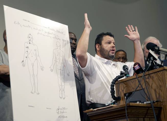 Forensic pathologist Shawn Parcells speaks during a news conference to share preliminary results of a second autopsy done on Michael Brown Monday, Aug. 18, 2014, in St. Louis County, Mo. The independent autopsy shows 18-year-old Michael Brown was shot at least six times, and Parcells, who assisted former New York City chief medical examiner Dr. Michael Baden during the autopsy, said a graze wound on Brown's right arm could have occurred in several ways.