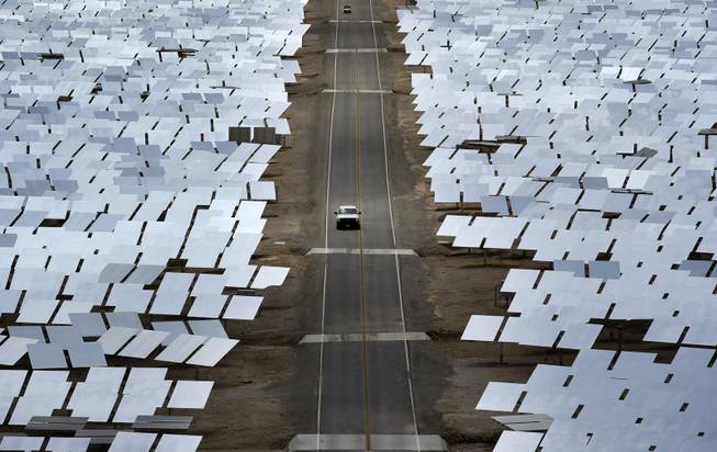 In this Aug. 13, 2014 photo, A truck drives through an array of mirrors at the Ivanpah Solar Electric Generating System near Primm, Nev. The site uses over 300,000 mirrors to focus sunlight on boilers' tubes atop 450 foot towers heating water into steam which in turn drives turbines to create electricity. New estimates for the plant near the California-Nevada border say thousands of birds are dying yearly, roasted by the concentrated sun rays from the mirrors.