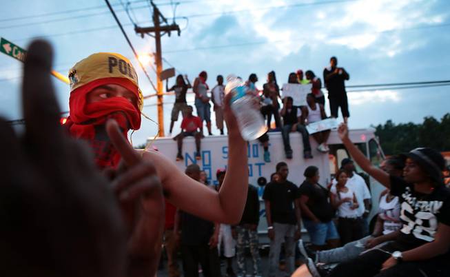 Protestors gather in Ferguson, Mo., Sunday, Aug. 17, 2014. On Saturday, Aug. 9, a white police officer fatally shot Michael Brown, an unarmed black teenager, in the St. Louis suburb. As night fell Sunday in Ferguson, another peaceful protest quickly deteriorated after marchers pushed toward one end of a street. Police attempted to push them back by firing tear gas and shouting over a bullhorn that the protest was no longer peaceful.