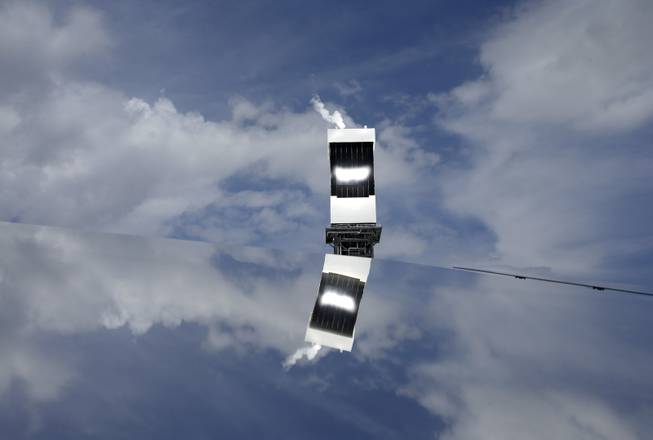 In this Aug. 13, 2014 photo, a power tower is reflected in a mirror on the ground at the Ivanpah Solar Electric Generating System near Primm, Nev. The site uses over 300,000 mirrors to focus sunlight on boilers' tubes atop 450 foot power towers heating water into steam which in turn drives turbines to create electricity. New estimates for the plant near the California-Nevada border say thousands of birds are dying yearly, roasted by the concentrated sun rays from the mirrors.
