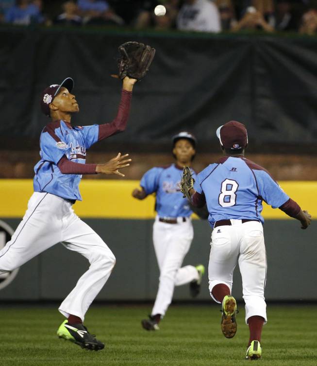 Philadelphia center fielder Kai Cummings, left, runs under a fly ball, that second baseman Jahli Hendricks (8) can't get to, hit by Las Vegas' Andrew Matulich, in the sixth inning of a United States semi-final baseball game at the Little League World Series tournament in South Williamsport, Pa., Wednesday, Aug. 20, 2014. Backing up on the play is right fielder Mo'ne Davis, center. Las Vegas won 8-1. (AP Photo/Gene J. Puskar)