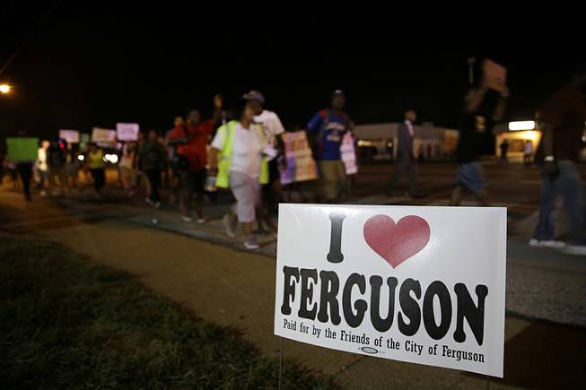 Protesters march Thursday, Aug. 21, 2014, in Ferguson, Mo. Protesters again gathered Thursday evening, walking in laps near the spot where Michael Brown was shot. Some were in organized groups, such as clergy members. More signs reflected calls by protesters to remove the prosecutor from the case.