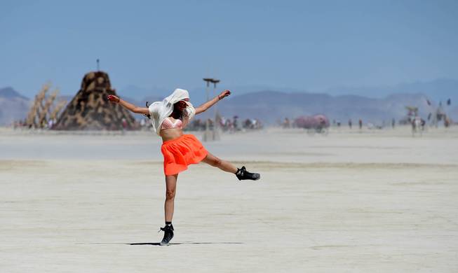 In this Aug. 27, 2014 photo, Franziska Goltz dances on the playa at Burning Man on the Black Rock Desert of Gerlach, Nev. Organizers call Burning Man the largest outdoor arts festival in North America, with its drum circles, decorated art cars, guerrilla theatrics and colorful theme camps.