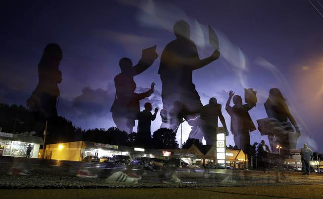 FILE In this Aug. 20, 2014 file photo taken with a long exposure, protesters march in the street as lightning flashes in the distance in Ferguson, Mo. On Aug. 9, a white police officer fatally shot unarmed Michael Brown, a black 18-year-old, in the St. Louis suburb. Rappers, like Talib Kweli, J. Coyle, and Lauryn Hill and others, are making their voices heard in song and on the ground in Ferguson, Missouri, in the wake of Mike Brown’s death, channeling hip-hop’s earlier roots when the genre worked as a voice for the oppressed and spoke out against injustice.