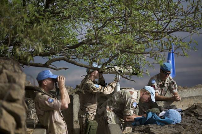 U.N. peacekeepers from the United Nations Disengagement Observer Force, also known as UNDOF, observe Syria's Quneitra province at an observation point on Mount Bental in the Israeli-controlled Golan Heights, overlooking the border with Syria, Friday, Aug. 29, 2014. An armed group detained more than 40 U.N. peacekeepers during fighting in Syria early Thursday and over 80 peacekeepers are trapped, the United Nations said.