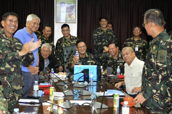 In this photo released by the Armed Forces of the Philippines Public Affairs Office, Philippine Military Chief Gen. Gregorio Catapang, center, reacts after learning about the safe repositioning of Filipino peacekeepers in Golan Heights as they monitor the situation with Philippine Foreign Affairs Secretary Albert Del Rosario, second left, Philippine National Defense Secretary Voltaire Gazmin, third from left seated, at Camp Aguinaldo military headquarters in suburban Quezon city, Philippines, on Saturday, Aug. 30, 2014.