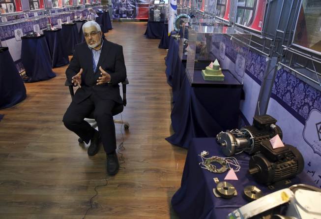 In this Monday, Sept. 1, 2014 photo, deputy head of the Atomic Energy Organization of Iran Asghar Zarean speaks in an interview with Associated Press as he is seated in a display of various parts and equipment from valves and pumps to electro motors, modems and barometers that they say were exported to the country with alleged purpose of sabotage and spying on Iran’s nuclear facilities, in Tehran, Iran. Zarean told The Associated Press Monday that the Islamic Republic has disrupted plots by foreign spies to recruit its nuclear experts.