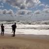 Photo: Beachgoers stand at the edge of the water Sunday, Photo: Beachgoers stand at the edge of the water Sunday,
