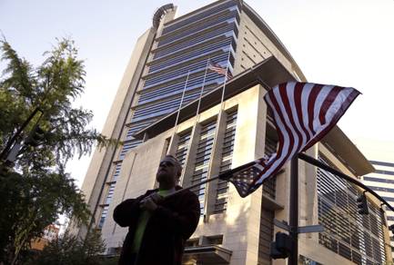 A protester flies an upside-down American flag outside the federal courthouse in Portland, Ore., Tuesday, Sept. 13, 2016. The Bundy brothers, Ammon and Ryan, and five others are on trial nine months after the armed occupation of a wildlife refuge in Oregon.